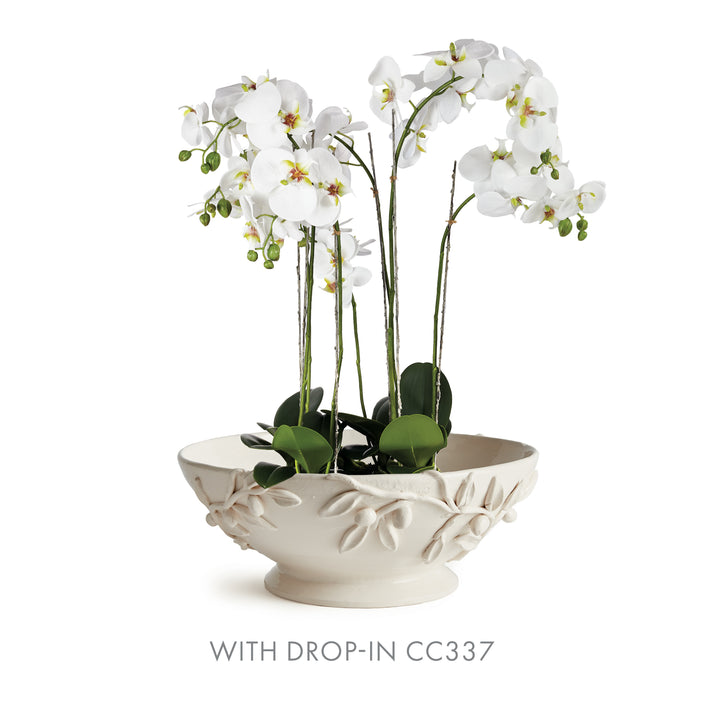 White olive relief bowl displayed with a tall white orchid arrangement, with green leaves above its raised rim. Traditional