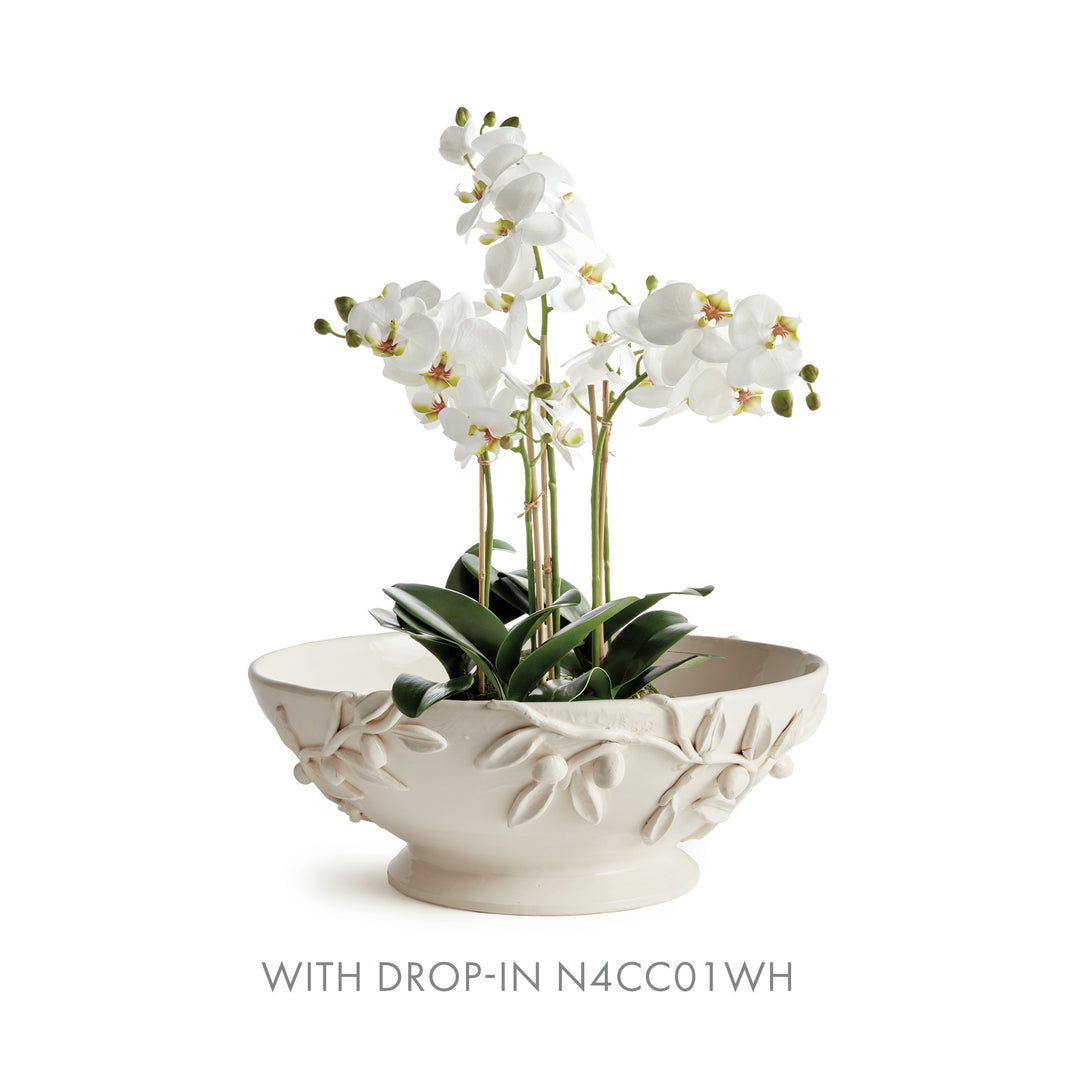 White olive relief footed bowl displayed with a smaller white orchid arrangement and green leaves above the rim. Traditional