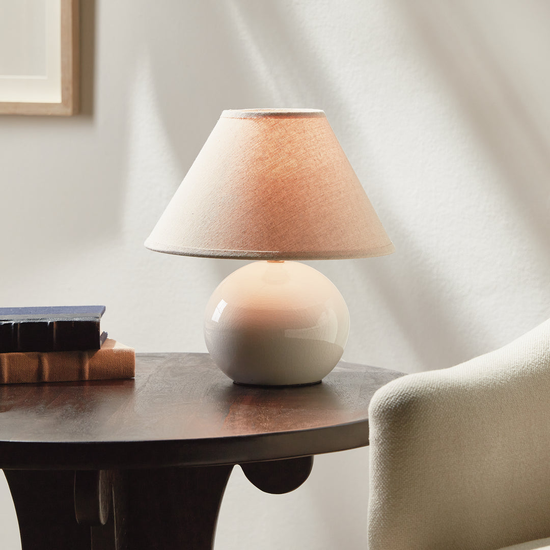 White mini ceramic table lamp with linen shade styled on bedside table in bedroom warm ambient modern accent lighting style