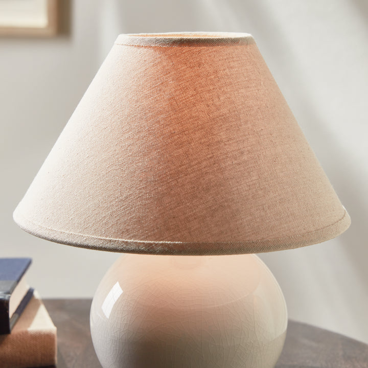 White mini ceramic table lamp illuminated on side table in interior room setting modern accent lighting style