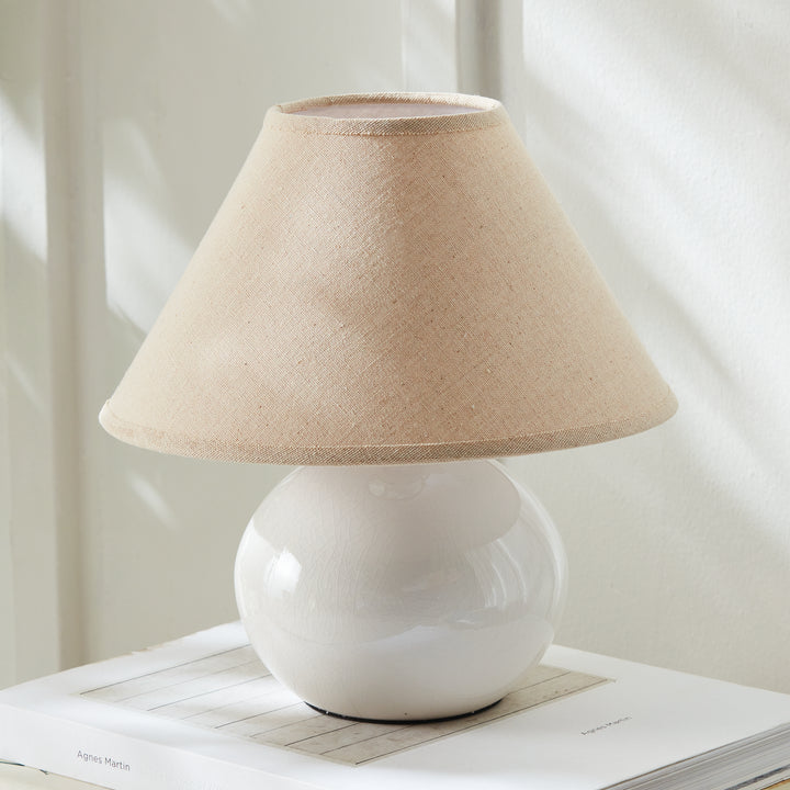White mini ceramic table lamp with linen shade angled side view on tabletop modern accent lighting style
