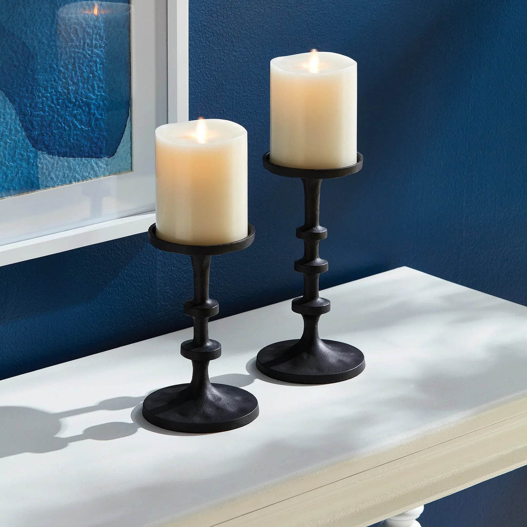 Industrial black bronze candle holders set of 2 styled on console against dark blue wall with glowing pillar candles – Transitional