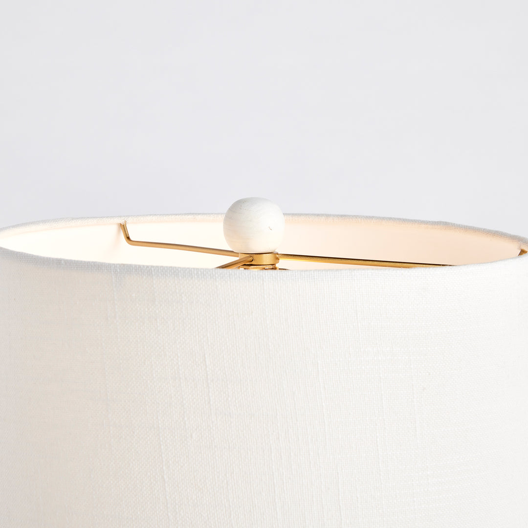 Close-up of mango wood table lamp finial with gold harp and clean white linen shade edge in crisp finish
