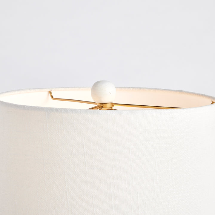 Close-up of mango wood table lamp finial with gold harp and clean white linen shade edge in crisp finish
