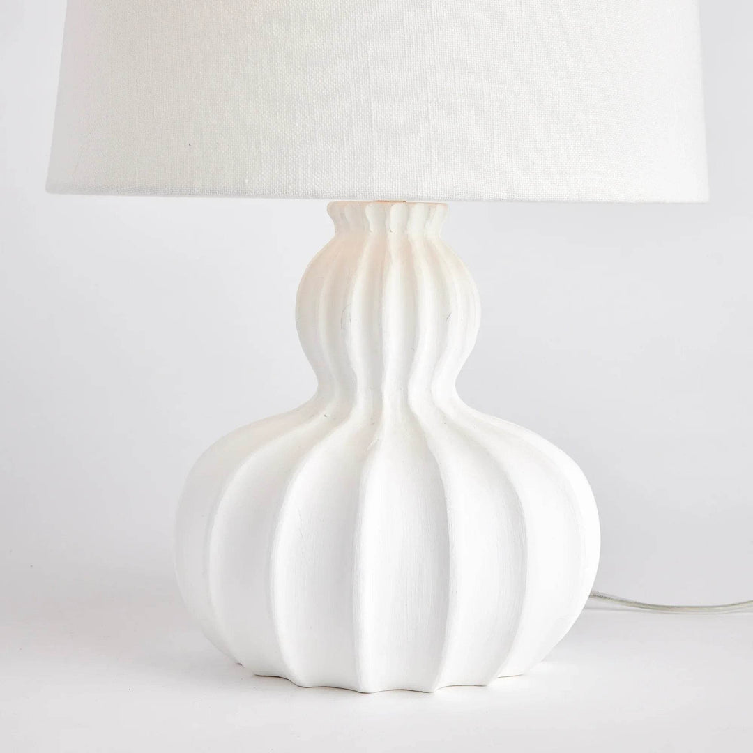 Side angle of white mango wood table lamp showing sculptural curves and linen drum shade in natural light

