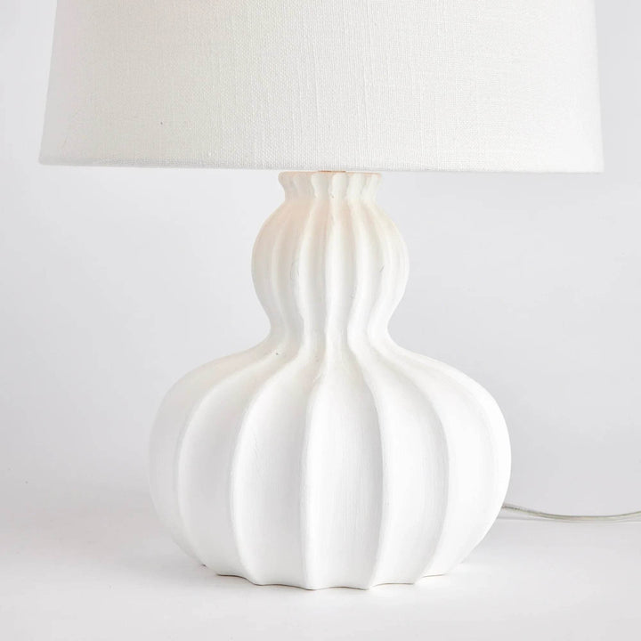 Side angle of white mango wood table lamp showing sculptural curves and linen drum shade in natural light
