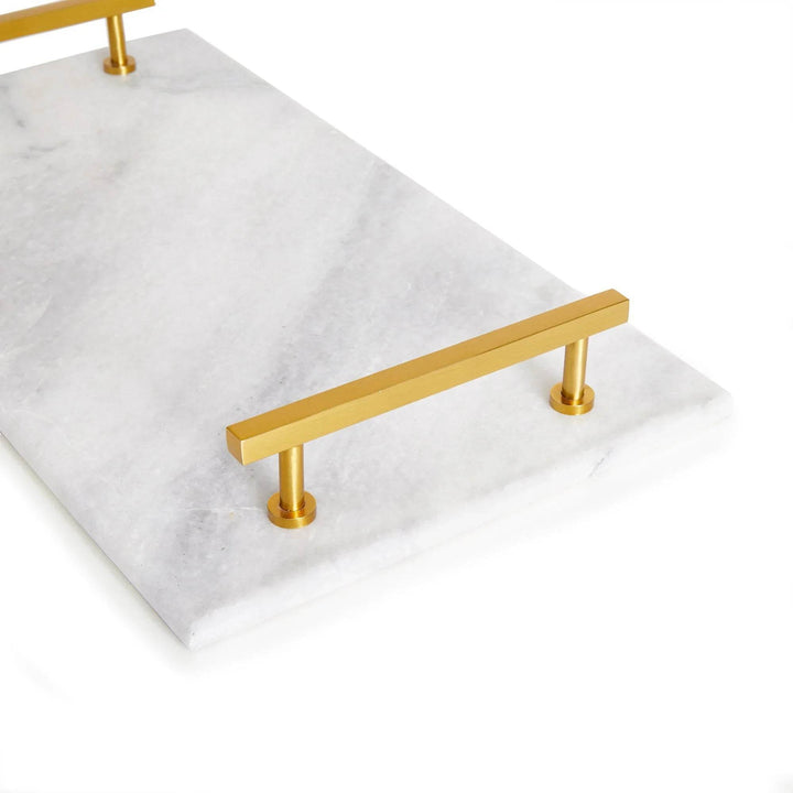 Close-up angled view of gold handle on white marble serving tray, showing natural veining – Coastal Glam.

