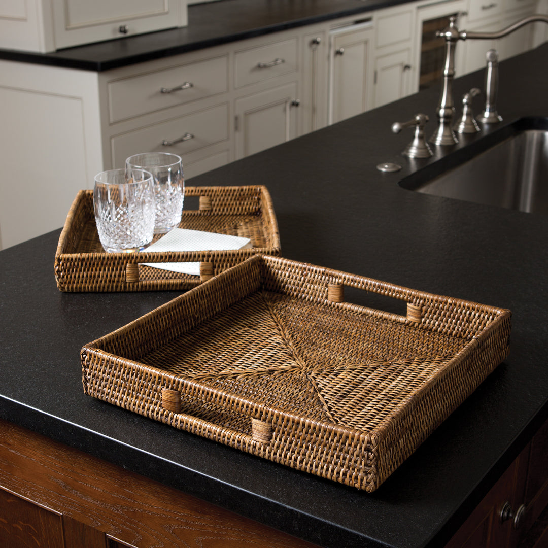 Brown square rattan tray set on a dark kitchen counter, with glasses arranged in the smaller tray - Coastal Transitional