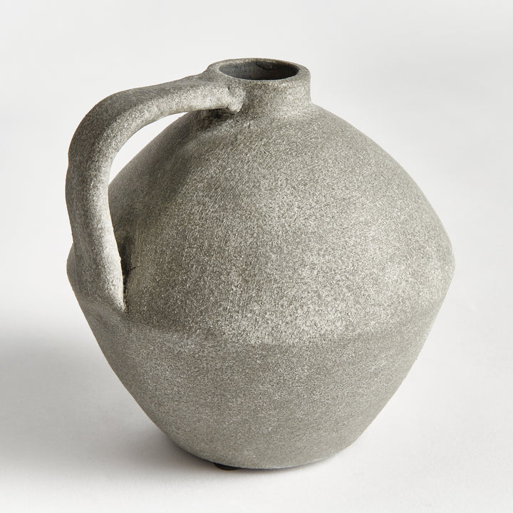 Rear view of a gray terracotta jug vase with rounded body, short neck and curved handle over mottled surface. Modern Organic