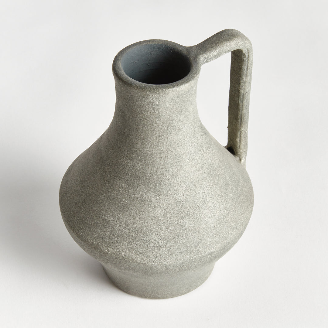 Angled view of a gray terracotta jug vase with a long open neck, flared body and tall handle beside the neck. Modern Organic