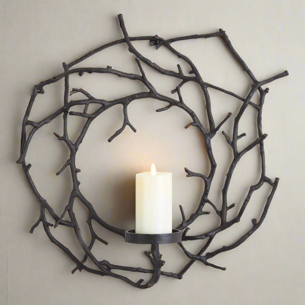 Matte black wall candle holder with rustic branch design mounted against a neutral wall in a minimalist setting.
