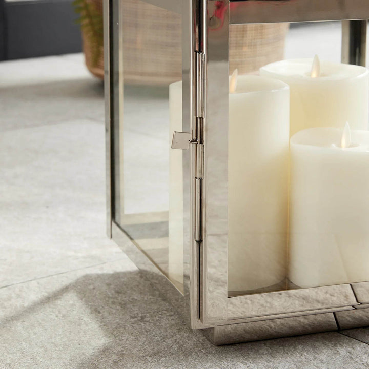 Close-up of medium silver lantern with large white pillar candles inside