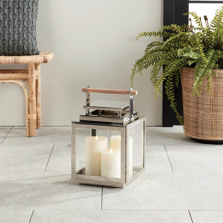 Medium Modern Coastal Outdoor Lantern styled on a patio with teak handle and silver frame