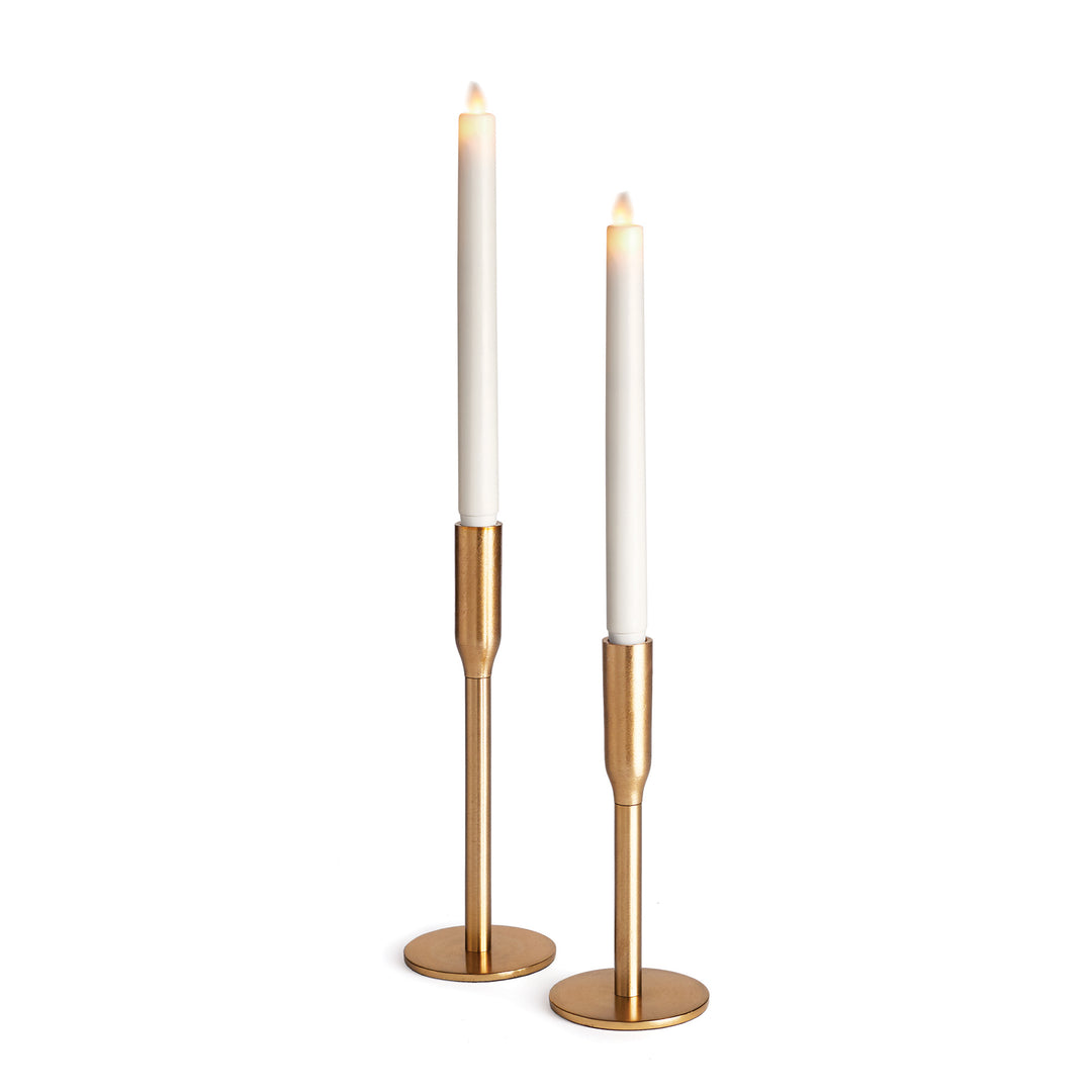 Pair of antique brass finish taper candle holders in two heights, with round bases and white LED tapers shown - Transitional