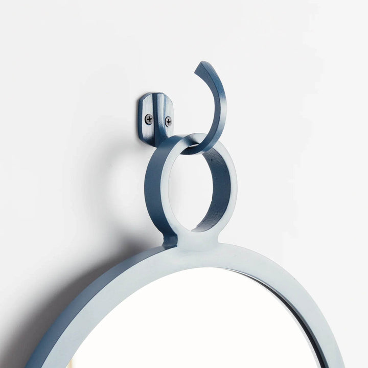 Close-up of hanging hook in matte blue finish on modern round mirror—perfect for coastal and minimal interiors