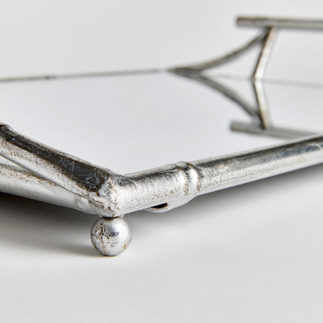 Corner detail of mirrored tray showing antique silver bamboo-style frame and ball feet

