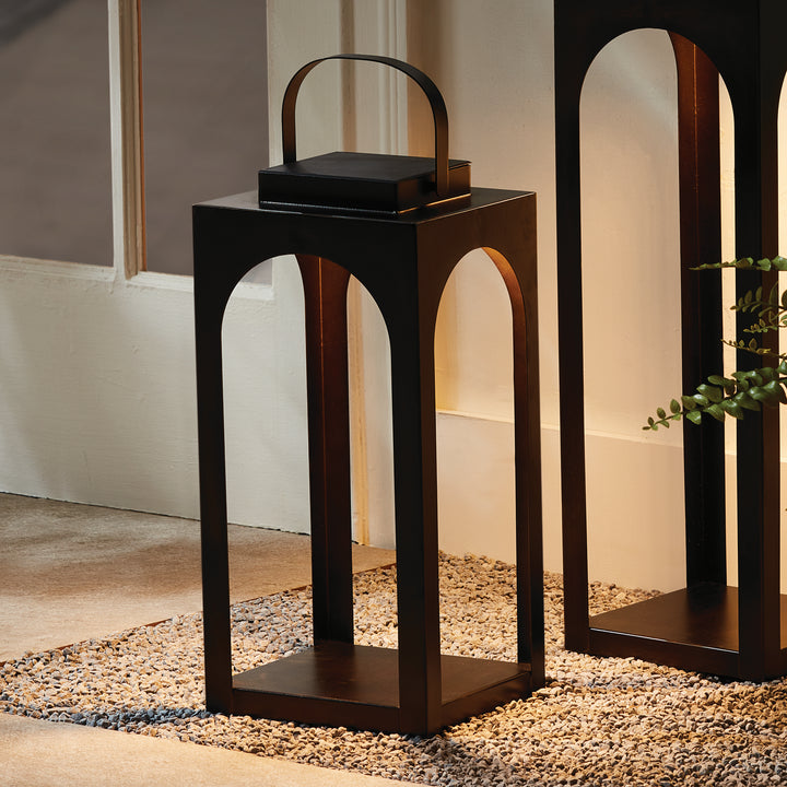 Modern arched solar LED outdoor lantern styled on a covered patio with warm ambient lighting beside outdoor seating – Transitional