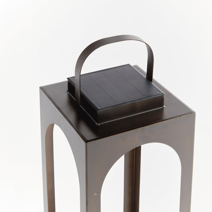 Close-up of the integrated solar panel and carry handle on a modern arched solar LED outdoor lantern – Transitional