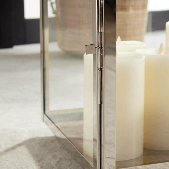 Close-up of large modern coastal lantern with pillar candle glowing inside.