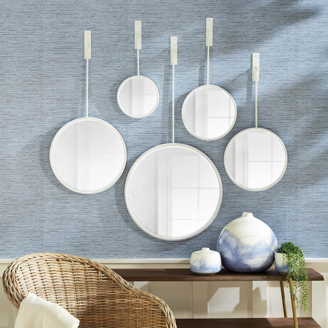 Entryway styled with five modern white round mirrors on a blue wall, suspended above console and ceramics
