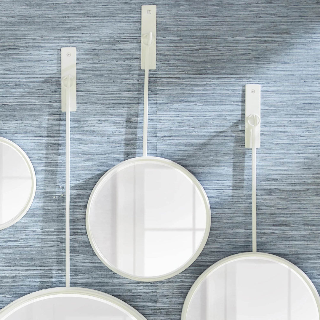 Close-up of modern round white wall mirrors suspended from slim rods in a sculptural coastal arrangement