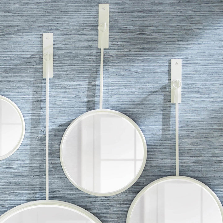 Close-up of modern round white wall mirrors suspended from slim rods in a sculptural coastal arrangement