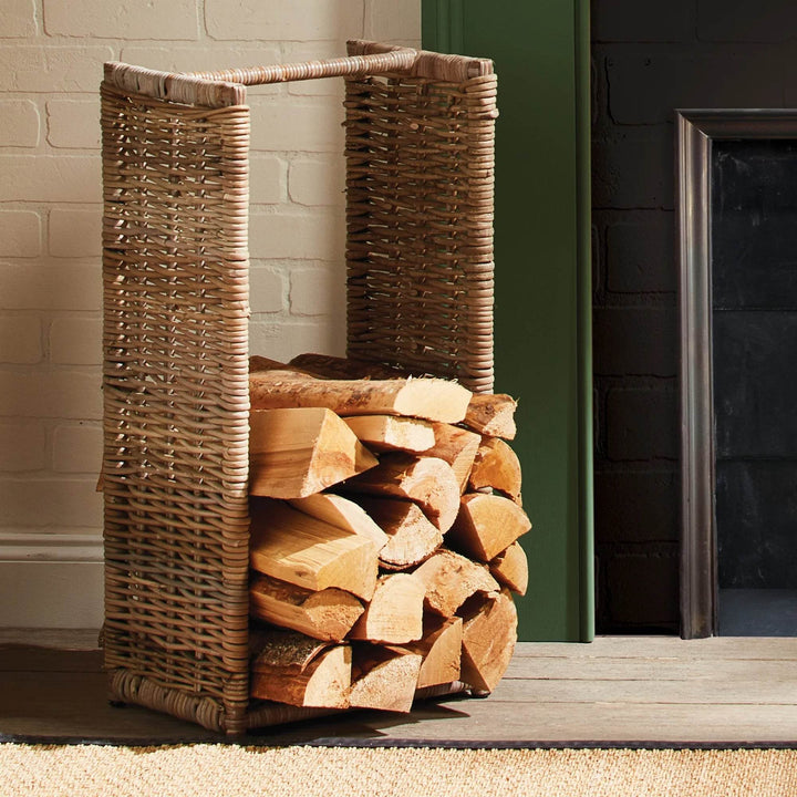Woven rattan log basket styled beside fireplace with stacked wood, rustic modern farmhouse firewood holder