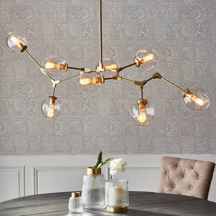 Antique brass globe chandelier styled above a round dining table in a soft mid-century modern space.