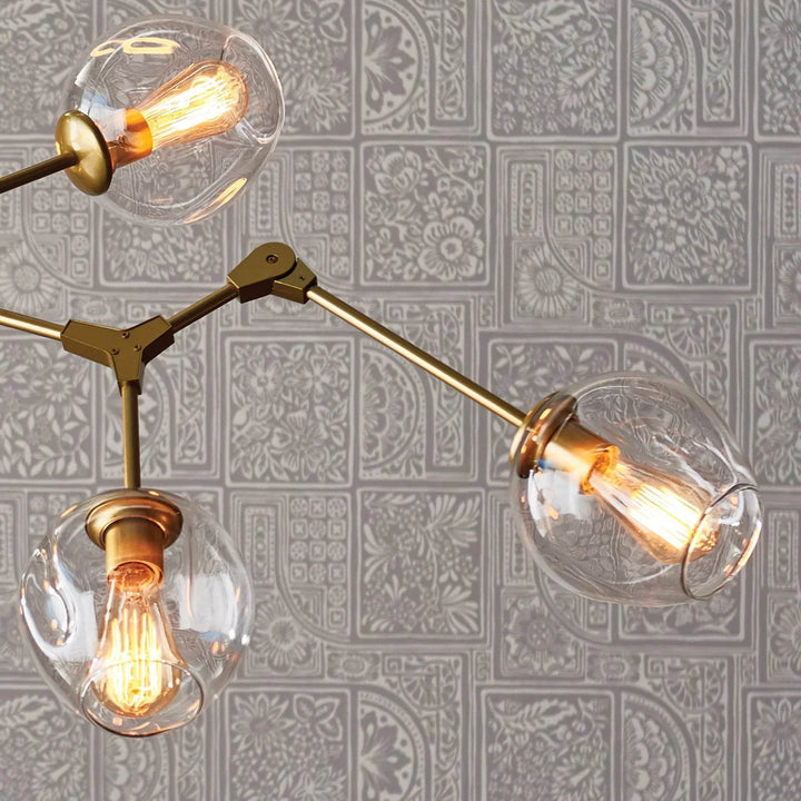Mid-century chandelier in antique brass suspended above a tufted dining setup with ribbed glass accents.

