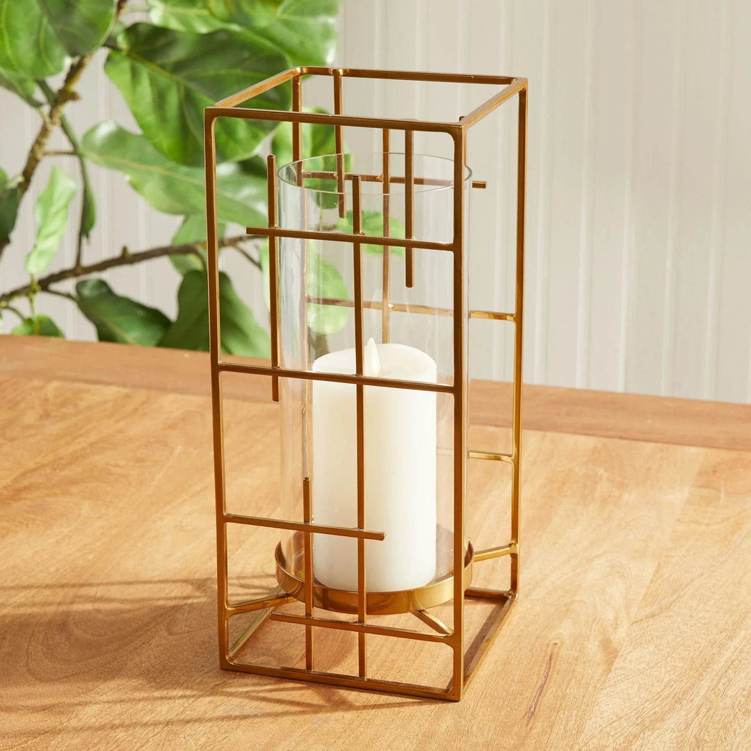 Gold metal hurricane holder with cylindrical glass insert, styled on wood table with greenery – Art Deco Revival

