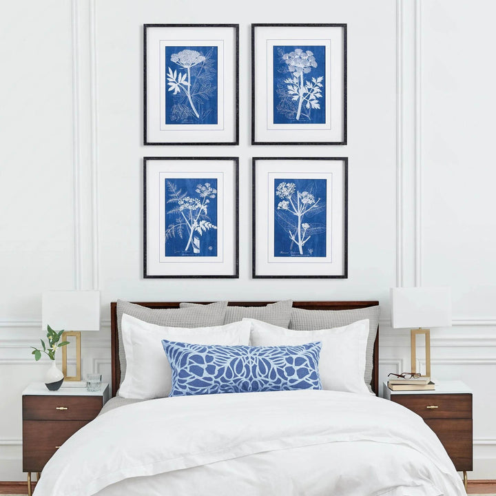 Blue botanical wall art set of 4 displayed above bed in clean white room, framed in black with white matting for modern heritage tone.
