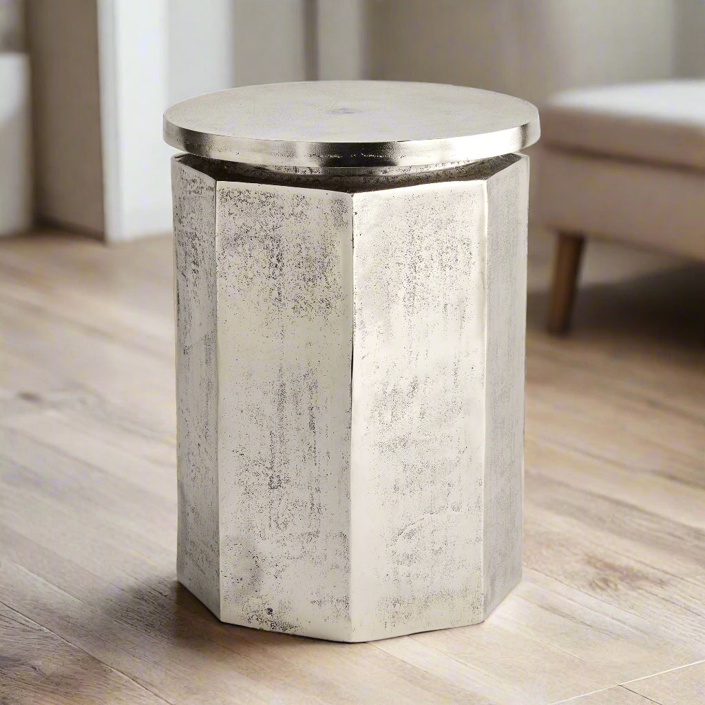 Silver industrial stool styled as accent table in modern interior with wood flooring

