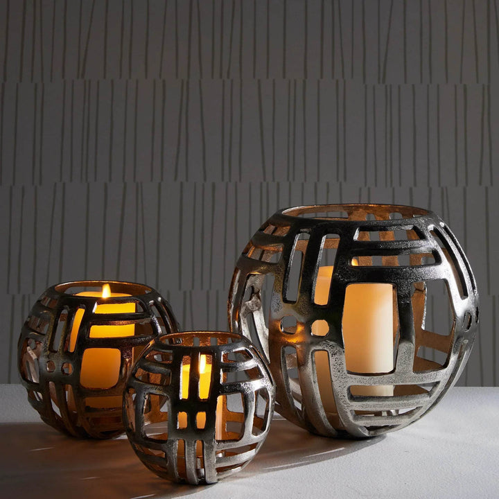 Set of modern industrial silver hurricane candle holders in large, medium, and small sizes, styled with LED candles on console table.

