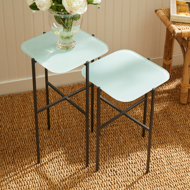 Minimalist glass-topped side tables beside armchair with natural lighting