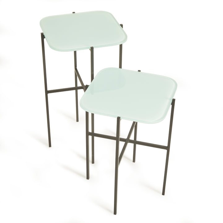 Close-up of icy blue modern nesting tables showing sleek glass and iron frame