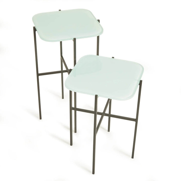 Close-up of icy blue modern nesting tables showing sleek glass and iron frame