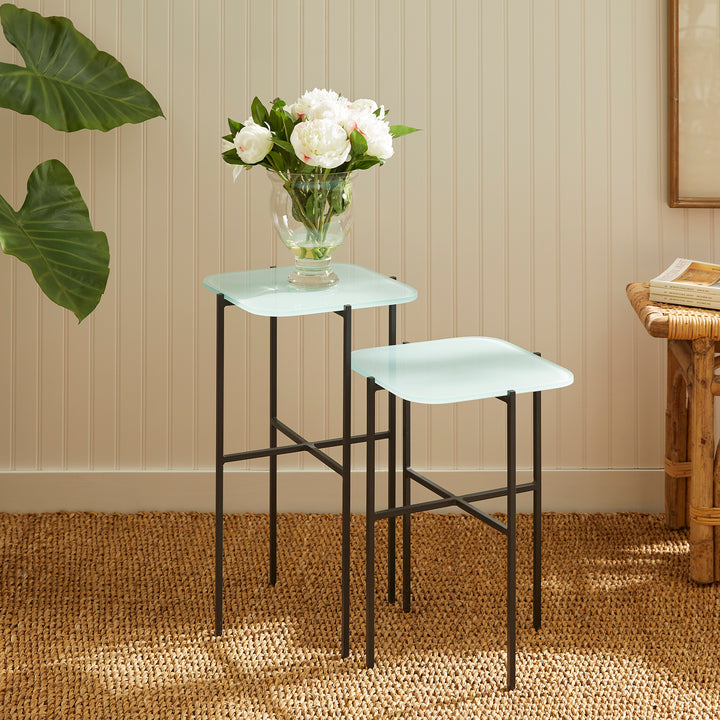 Blue glass side tables styled with flowers beside neutral wainscoting wall