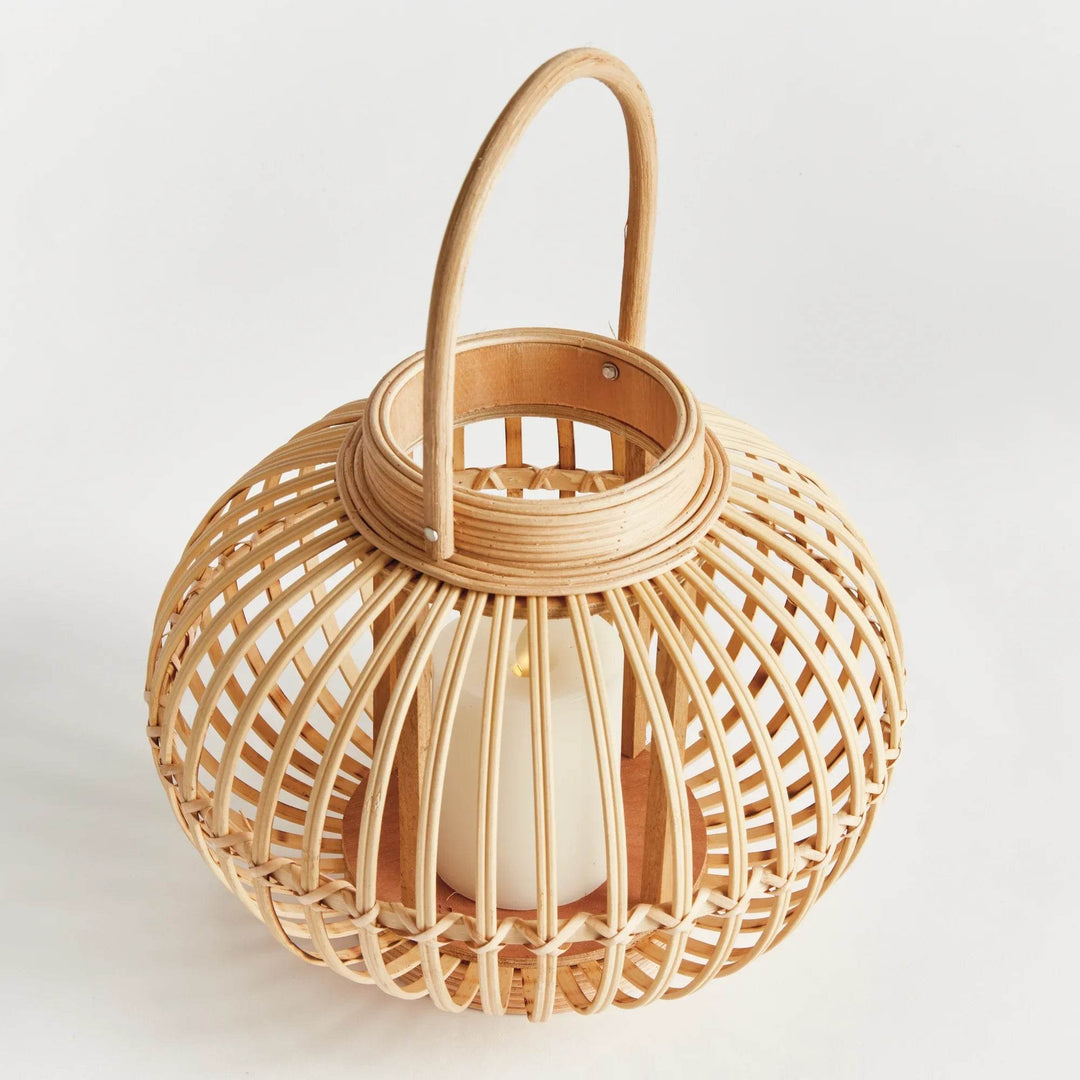 Small rattan lantern with upright handle, featuring coastal boho weave and warm natural finish.

