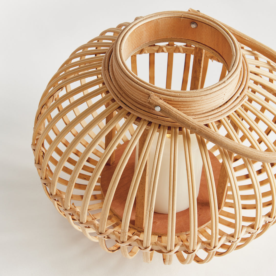 Top view of small modern natural rattan lantern showing bamboo weave and coastal boho style handle.

