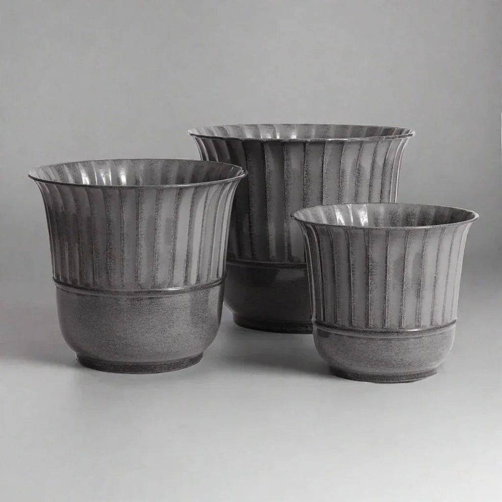 Set of three gray metal planters with vertical grooves shown at an angled indoor view