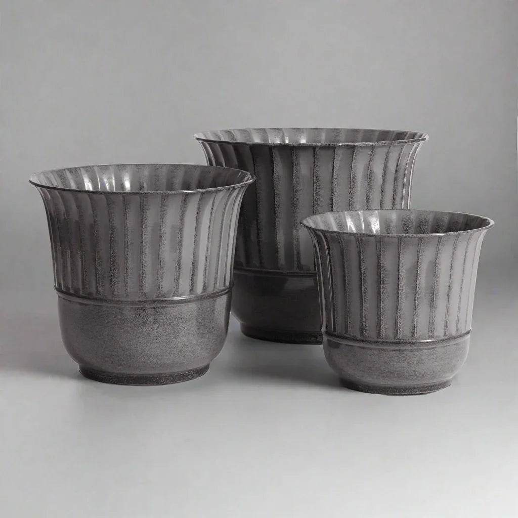 Set of three gray metal planters with vertical grooves shown at an angled indoor view