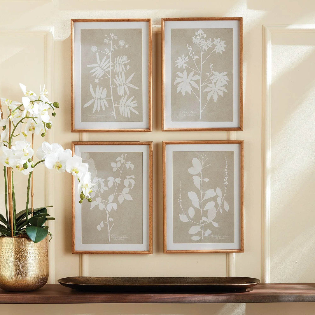 Taupe and white botanical wall art set of four shown styled with gold vase and orchid.