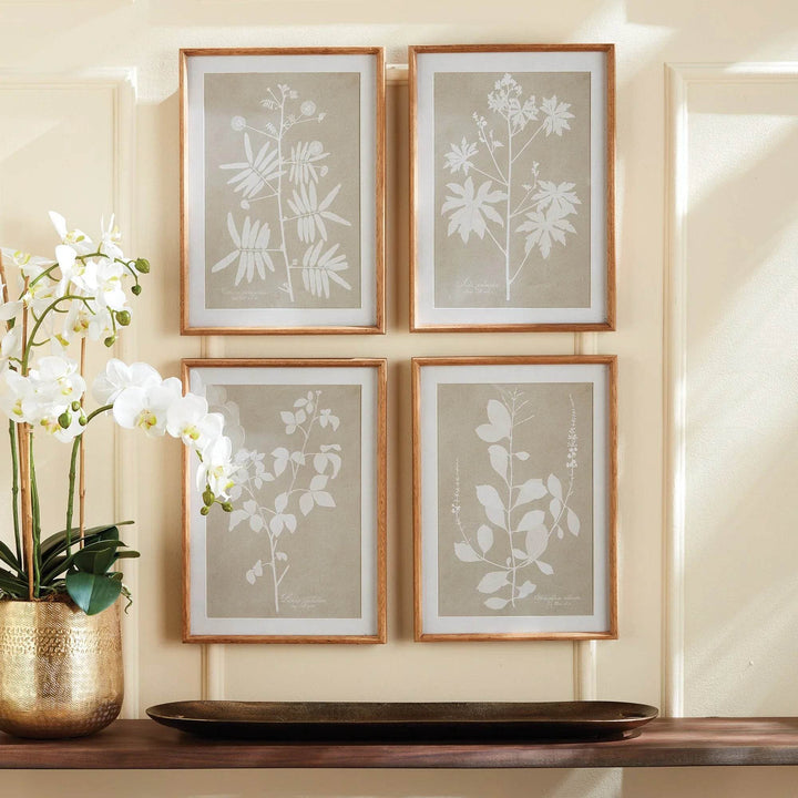 Taupe and white botanical wall art set of four shown styled with gold vase and orchid.