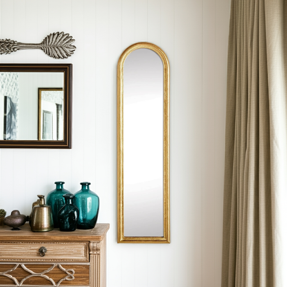 Narrow arched gold wall mirror in entryway; 50 x 13 inches adds height and reflected light to compact spaces – Transitional.