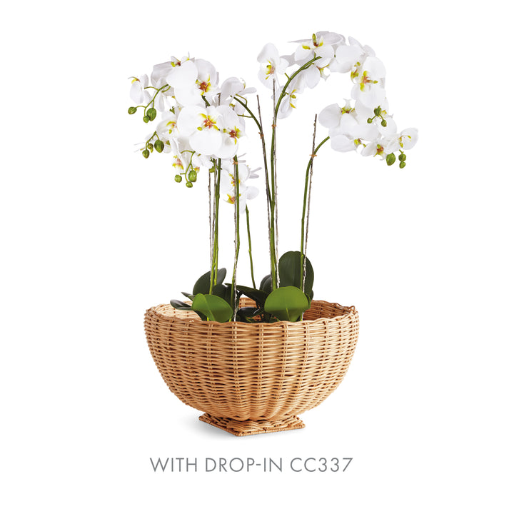 Natural rattan footed bowl styled with white orchid flowers and green foliage above its woven rim - Coastal Transitional