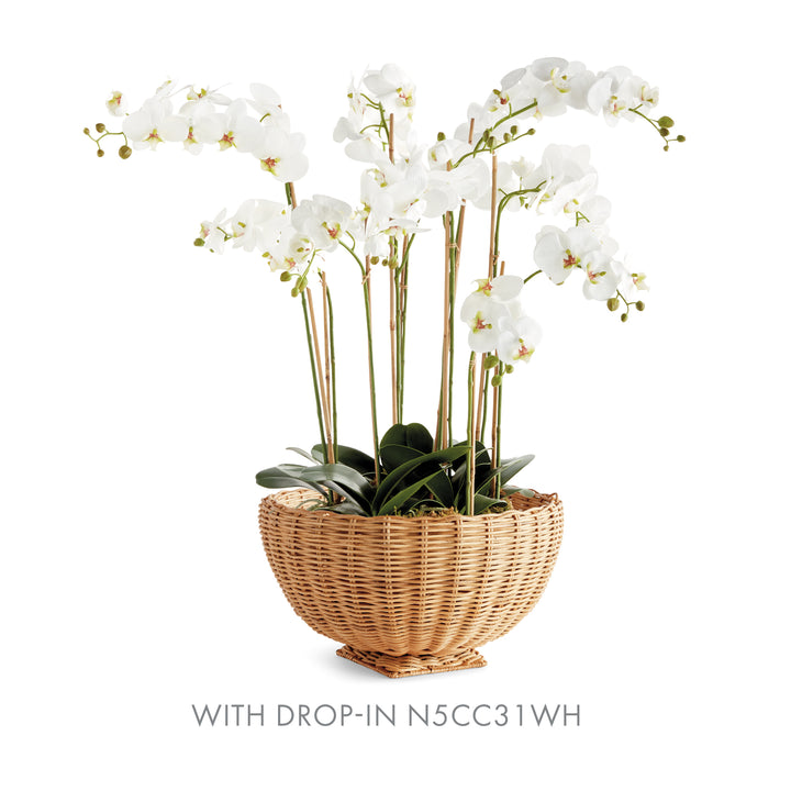 Natural rattan footed bowl holding tall white orchids with slim support stakes, shown on plain white - Coastal Transitional