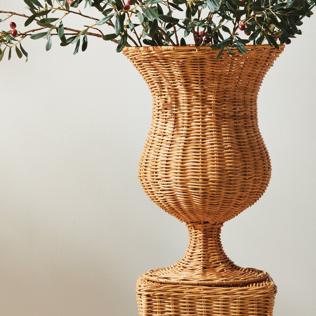 Tall natural handwoven rattan footed urn styled with faux olive branches in a warm organic interior – Coastal.