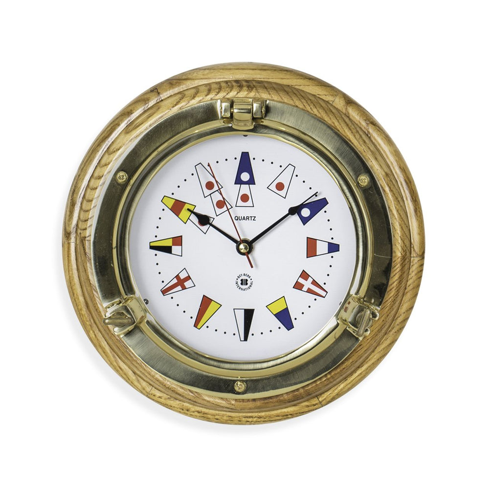 Brass porthole wall clock with nautical flags dial shown angled front view for yacht office coastal decor style