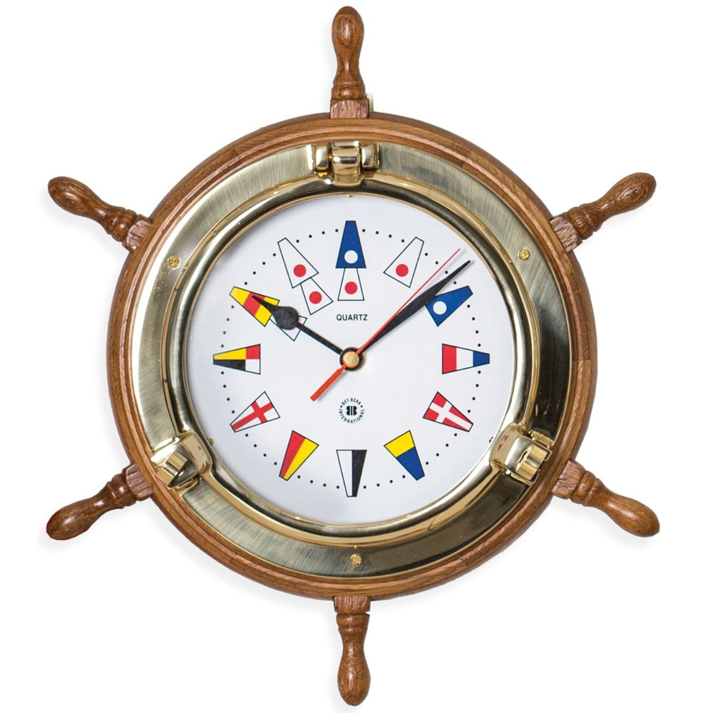 Brass ship wheel wall clock with oak frame and nautical flags dial shown front angle for coastal office decor style