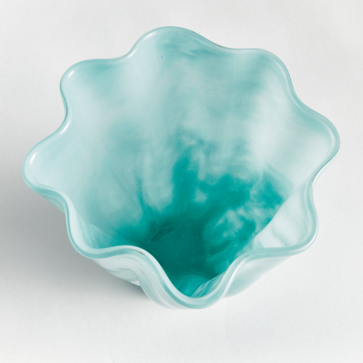 Overhead view of a light blue glass vase showing the flower-like waved opening and watercolor-inspired mottled color. Coastal